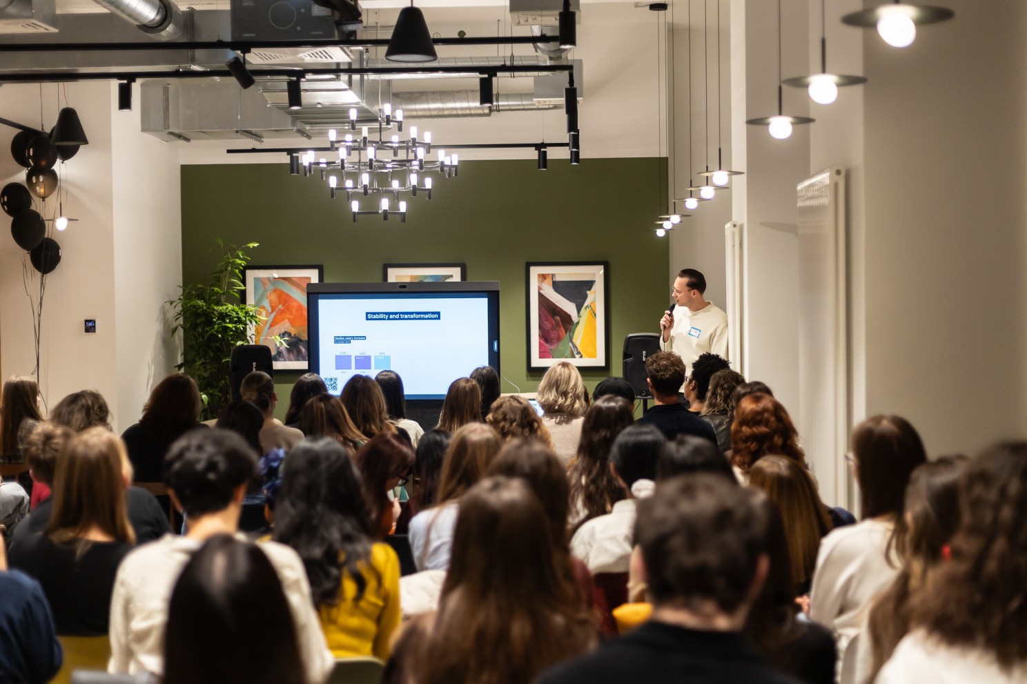 A packed Talent Crunch event — speaker on a microphone presenting to a full room of attentive talent professionals.