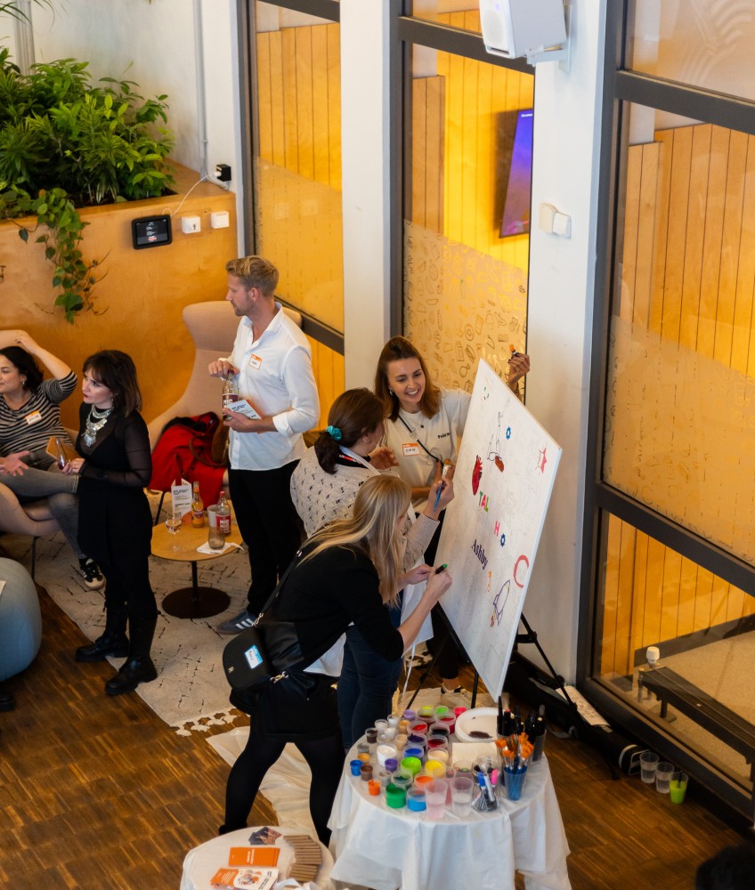 A Talent Crunch experiential event — members collaborating on a painted canvas while others mingle in the background.