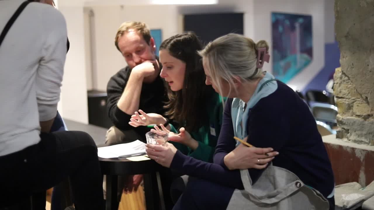 Members in conversation during a Talent Crunch workshop — three people leaning in around a small table, deep in discussion.